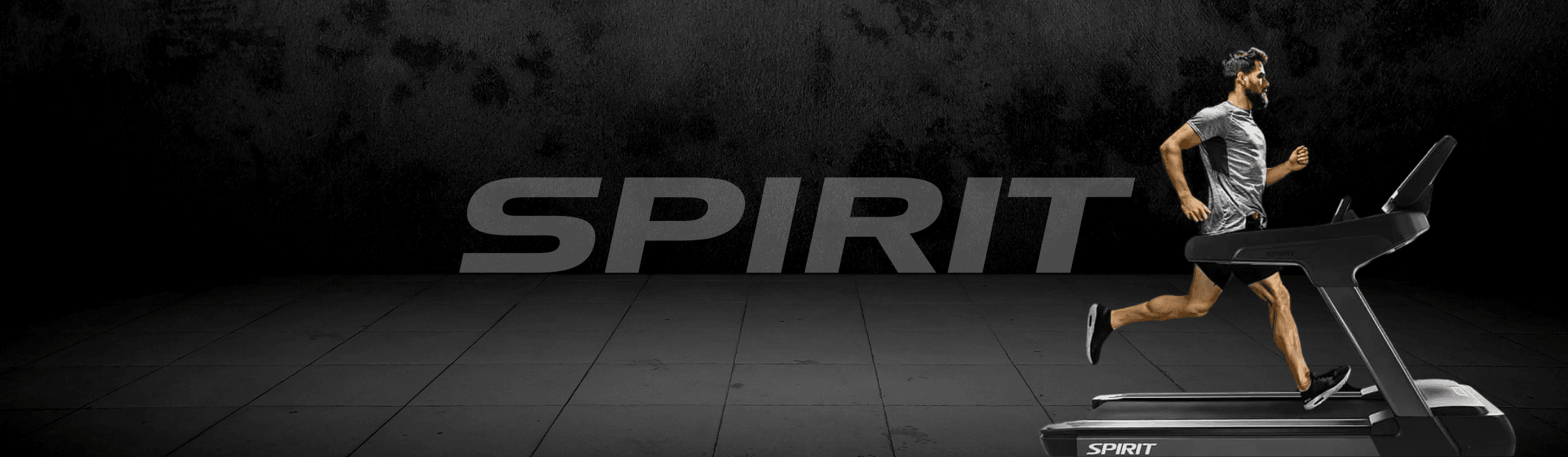 Man running on a treadmill in a dimly lit gym. Spirit brand cardio equipment, highlighting technology, performance, and durability.
